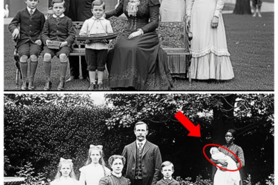 This mysterious 1901 photo holds a secret that experts have tried to explain for decades.  Dr.Elena Vasquez had spent 20 years restoring historical photographs, but she had never seen anything quite like this.  It was a humid August morning in 2024, and she sat in her studio in Cambridge, Massachusetts, examining a photograph that had been brought to her by the Boston Historical Society.  The image dated 1901 showed the wealthy Thornton family of Beacon Hill posing in their elaborate garden.  The photograph was a masterpiece of early 20th century portraiture.  The Thornton family stood arranged on their manicured lawn, the patriarch Richard Thornon in the center, his wife Catherine beside him, their three daughters in white laced dresses, and a young boy of perhaps 5 years old standing between the parents.  Behind them rose their impressive brownstone mansion, and carefully trimmed hedges framed the composition.  Elena had been hired to digitally restore the photograph, which had suffered water damage and fading over the decades.  She scanned the image at extremely high resolution, then began the painstaking work of removing stains, adjusting contrast, and sharpening details that time had blurred.  It was during this process, while working on the background elements that she noticed something unusual.
