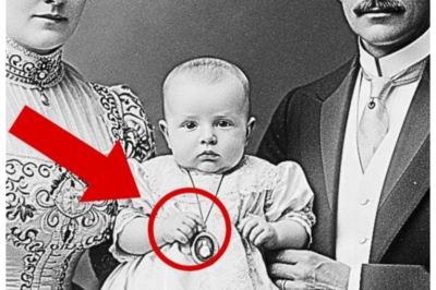 This 1910 portrait seems harmless.  When Experts discover what the baby is holding, they’re shocked  The October wind rattled the windows of the Vandermir estate in upstate New York as Dr.  Sarah Chen navigated through rooms filled with a century of accumulated possessions.  As a specialist in early American photography at the Metropolitan Museum of Art, she’d been called to assess a collection before the property’s final sale.  Sarah moved carefully through the library, surrounded by mahogany bookcases and family portraits spanning generations.  One portrait stopped her mid-stride.  A formal studio photograph from around 1910.  A distinguished couple in their 40s sat in elaborate period dress.  Between them, cradled awkwardly in the woman’s arms, was an infant dressed in white silk and lace.  Something felt wrong.  The couple held the baby stiffly, as if unfamiliar with the weight.  Most infants in photographs from this period appeared blurred or startled.  This baby seemed eerily calm, almost unnaturally so.