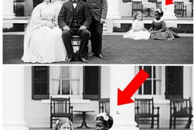 It was just a family portrait — until historians discovered the truth about the child  It was just a family portrait until the historians discovered the truth about the child.  The photograph arrived at the Massachusetts Historical Society in a worn leather portfolio donated by the estate of Elizabeth Hartwell, a retired school teacher from Boston who had passed away at 93.  Among dozens of family documents, this particular image stood out.  A formal portrait from 1889, sepiaoned and remarkably well preserved, showing a wealthy family posed in their grand parlor.  Dr.Rachel Montgomery, a historian specializing in post Civil War America, carefully lifted the photograph from its protective sleeve.  The image showed a prosperous family, a stern-faced father in a dark suit with a watch chain gleaming across his vest, a mother in an elaborate dress with leg of mutton sleeves, and two older children, a teenage boy and girl standing rigidly beside their parents.  The room behind them spoke of wealth.  Ornate wallpaper, heavy draperies, and expensive furniture gleamed in the photographers’s flash powder light.  Rachel had examined hundreds of portraits from this era, but something about this one caught her attention.  In the background, slightly out of focus, two small figures sat on an expensive Persian rug.