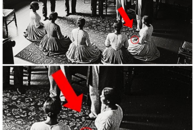 It was just a formal family gathering — but one detail revealed a horrifying truth  It was just a formal family gathering, but one detail revealed a horrifying truth.  Dr.Sarah Mitchell stood in her office at the National Museum of American History in Washington, DC on a cold January morning in 2025, carefully unwrapping a package that had arrived without warning 3 days earlier.  As the museum’s lead curator for 19th century social history, she received donations regularly.  But this one had arrived with unusual circumstances.  No return address, no accompanying letter, only a small note card tucked inside that read, “This photograph has been hidden in my family for 150 years.  It’s time the truth was known.  ” The frame was heavy, ornate mahogany with intricate carvings typical of the 1870s.  As Sarah lifted away the final layer of protective wrapping, the photograph itself came into view.  A large format album in print, remarkably well preserved, mounted on thick cardboard backing.  The image showed a formal interior scene, a spacious room with tall windows casting dramatic light across wooden floors and ornate carpet in the center and simple but elegant furniture arranged around the space.  But it was the people in the photograph that immediately captured Sarah’s attention.