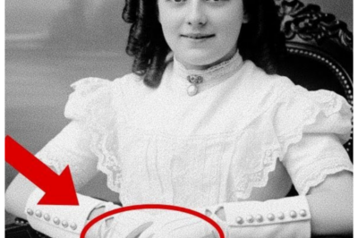 A 1904 Studio Photo Looks Harmless — But the Girl’s Hands Reveal a Frightening Detail  A 1904 studio photo looks harmless, but the girl’s hands reveal a frightening detail.  Professor David Richardson carefully arranged the collection of vintage photographs on his desk at the Boston Historical Archive.  Each one a window into America’s past.  The late afternoon sun filtered through the tall windows of his office, casting golden light across the sepia toned images that had arrived that morning from the Peton estate sale.  Among dozens of typical family portraits from the early 1900s, one photograph immediately caught his attention.  Not for any obvious reason, but for its seeming perfection, the 1904 studio portrait showed a young girl, perhaps 12 or 13 years old, seated in an ornate Victorian chair against a painted backdrop of pastoral scenery.  She wore a pristine white dress with delicate lace trim, her dark hair arranged in the elaborate ringlets fashionable for children of wealthy families.