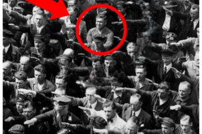 It Was Just Another Photo of German Workers – But Pay Attention to the Man with Crossed Arms Professor David Mitchell had seen thousands of photographs from Nazi Germany. As a history professor at Columbia University specializing in World War II, his office walls were covered with images of rallies, marches, and public ceremonies. But on a cold October morning in 1991, while reviewing archival materials from Hamburg’s state archive, one particular photograph stopped him cold. The image showed hundreds of civilian workers gathered at the Blom Plus shipyard in Hamburg, June 13th, 1936. They were attending the launch of the horse vessel, a training vessel for the German Navy. Shipyard employees, dock workers, foremen, engineers, ordinary working men assembled for a ceremonial event. The scene was typical of the era. A sea of raised arms performing the Nazi salute, faces turned towards something outside the frame, probably a Nazi official or party leader. Row after row of identical gestures, a choreographed display of conformity and allegiance.