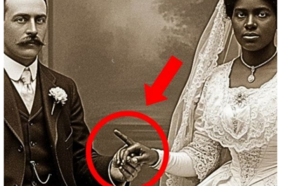 It was just a wedding photo — until you zoomed in on the bride’s hand and discovered a dark secret It was just a wedding photo until you zoomed in on the bride’s hand and discovered a dark secret. The afternoon light filtered through the tall windows of the Atlanta Historical Archive as Dr. Rebecca Morrison carefully examined a collection of early 20th century photographs donated by an anonymous estate among faded portraits and formal gatherings. One image stopped her cold. A wedding photograph from 1903. A white man in a dark three-piece suit sat rigidly beside a black woman in an elaborate white wedding gown. Their hands were clasped between them in what should have been a gesture of unity. Rebecca’s 15 years as a historical archivist had taught her to notice anomalies. This photograph screamed wrongness on multiple levels. In 1903, Georgia, interracial marriage wasn’t just taboo, it was illegal. The state’s anti-misogenation laws in place since 1750 and strengthened after the Civil War made such unions criminal offenses punishable by imprisonment. Yet, here was photographic evidence of what appeared to be exactly that.